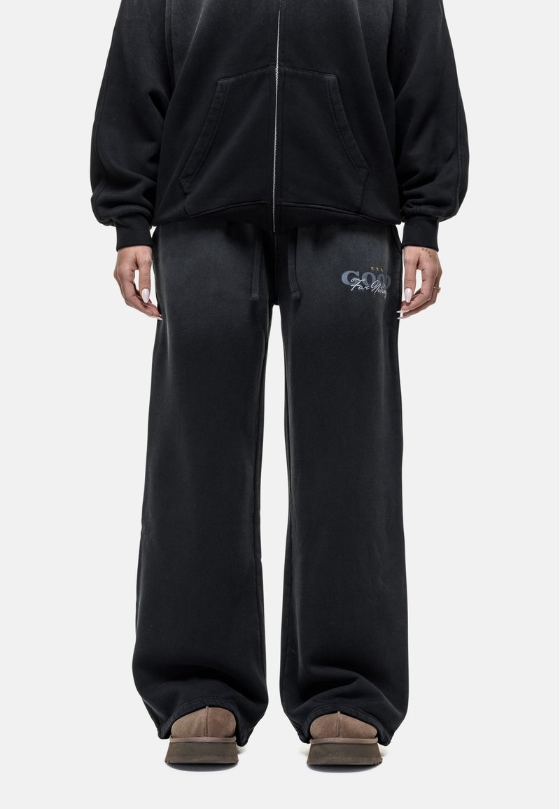 Zwarte katoenen oversized hoodie met rits en voorzakken, gecombineerd met zwarte sweatpants met een grafisch logo, een relaxte pasvorm en een trekkoord in de taille.