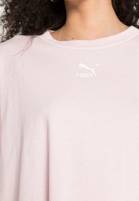 Jasnoróżowa koszulka z krótkim rękawem wykonana z miękkiej bawełny, z białym logo Puma na piersi i okrągłym dekoltem.