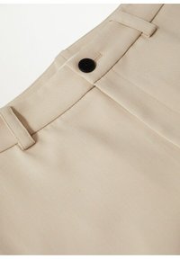 Pantalon beige à coupe droite, avec une fermeture à bouton noir, des détails cousus, et un tissu lisse et texturé.