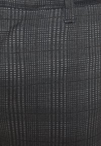 Zwarte stof met patroon in detail, met kleine horizontale en verticale lijnen. Zachte textuur, met een lichte glans, geschikt voor casual kleding.