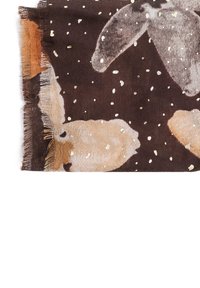 Sciarpa marrone con motivo floreale beige chiaro e spruzzi dorati. Il tessuto è morbido con un bordo sfrangiato, che aggiunge texture al design.