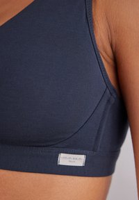 Navyblå trådlös bh gjord av mjukt tyg, har sömlösa sidor, ett brett band och en liten tygetikett med texten "intimissimi Natural".