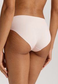 Mutande a vita alta in cotone di colore rosa chiaro con un design senza cuciture e una texture morbida. Presentano una cucitura minimale lungo i bordi.