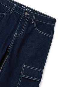Pantalones cargo de denim azul oscuro con costuras blancas, que cuentan con múltiples bolsillos y un cierre frontal con botón. La etiqueta dice "REPÚBLICA DEL DENIM".