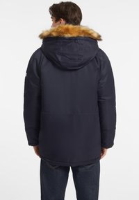 Chaqueta de plumas navy con capucha forrada de piel desmontable, que presenta una textura suave, mangas largas y un corte holgado. Incluye bolsillos laterales.