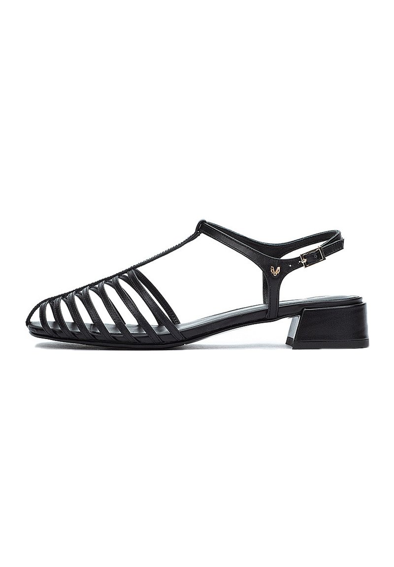 Sandalias negras con diseño abierto y ranurado, hechas de piel suave, con un tacón bajo y una correa ajustable con hebilla. Suela plana.
