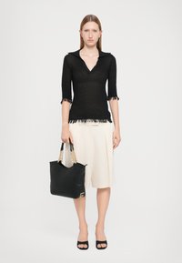 Black sheer knit top with a collar, fringed hem and sleeves; cream pleated midi skirt; black tote with gold chain handle; open-toe black heels.