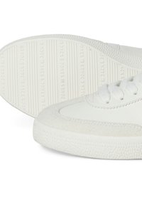 Weiße Sneaker mit einem glatten Lederoberteil und Wildlederakzenten, rutschfester Gummisohle und auffälliger Markenkennung auf der Sohle.