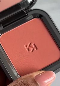 Colorete compacto de color coral mate; forma cuadrada; logo en relieve; en un estuche negro brillante con tapa transparente.