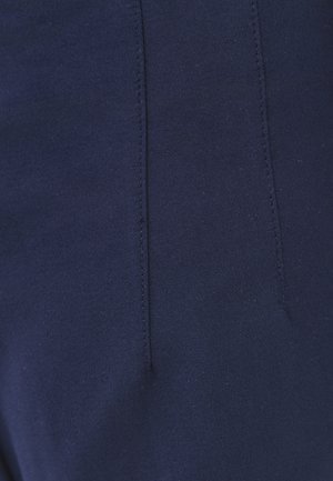 Close-up van donkerblauwe stof met verticale gestikte naden, met gedetailleerde textuur en fijne stiksels.