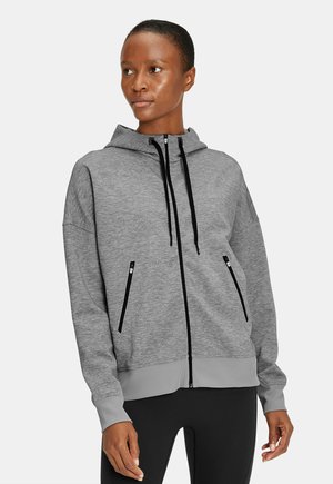 Hoodie zippé gris en tissu doux avec une finition texturée, présentant des accents de fermeture éclair noirs et une capuche avec cordon de serrage.