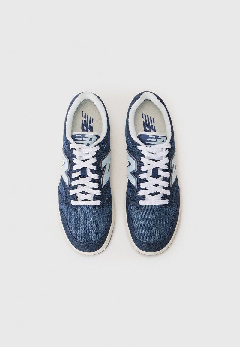 Blue denim sneakers feature white laces, light blue accents, and a cushioned tongue with a textured surface and rubber sole.