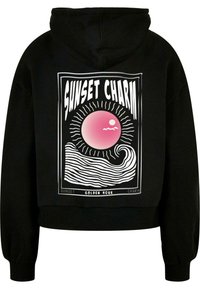 Svart hettegenser med cropped design, med grafisk trykk av en rosa sol og havbølger, rammet inn med hvit tekst. Myk tekstur, ribbede mansjetter.