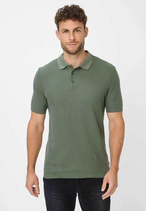 Groene polo met korte mouwen gemaakt van textuurstof, met een kraag en knoopsluiting met drie knopen, gecombineerd met donkere jeans.