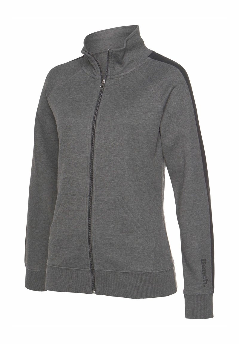 Šedá zipová mikina z měkkého materiálu, s vyšším límcem, bočními pruhy a předními kapsami. Logo na rukávu.