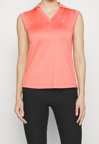Ärmlös polo i korall, gjord av mjukt och lätt tyg. Har en V-halsringning och krage, med en liten logotyp på bröstet.
