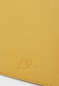 Nike wallet in bright yellow leather with smooth texture, featuring embossed logo and contrasting stitching along the edges.
