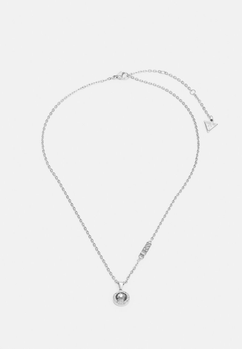 Silver kedja halsband med en rund hänge som har en central sten, prydd med en cirkulär kant. Inkluderar en liten logotag vid låset.