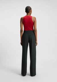 Top rosso senza maniche abbinato a pantaloni scuri a righe con vita alta. Tessuto liscio con un design aderente e una forma a gamba dritta e larga.