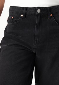 Jeans negre din denim cu un finisaj texturat, design cu cinci buzunare, accesorii de culoare cupru și închidere cu nasture la talie.