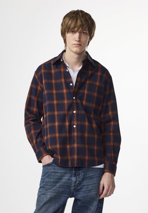 Marineblauw en oranje geruite flanellen overhemd met een knoopsluiting aan de voorkant, lange mouwen en een enkele borstzak, gecombineerd met denim jeans.