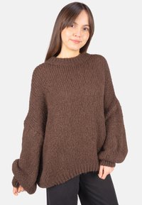 Brauner gestrickter Pullover mit lockerem Sitz, gerippter Struktur, weitem Ärmeln und Rundhalsausschnitt. Verfügt über einen dicken, gemütlichen Stoff.