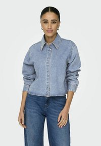 Light blue denim jacket with a collar, button closure, and long sleeves. Features a cropped design and subtle embellishments throughout.