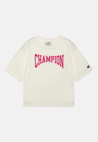 Camiseta de manga corta blanca hecha de algodón, con un gran logo rosa de "CHAMPION" en el pecho. Cuello redondo acanalado y logo en la manga.
