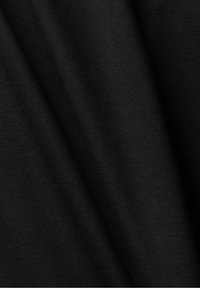 Tissu noir avec une texture tissée fine et des plis diagonaux doux créant des variations subtiles d'ombre.