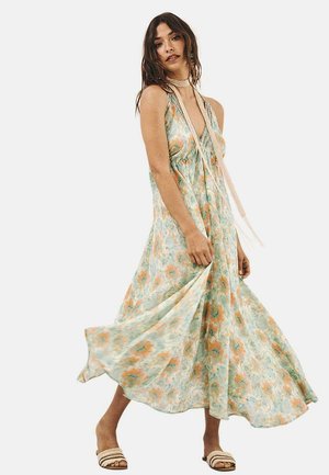 Vestido maxi floral de tejido ligero, con tonos de verde y naranja, de corte fluido y diseño de escote halter.
