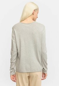 Lichtgrijze longsleeve top van zacht materiaal, met een ronde hals en subtiele stikdetails aan de zoom en mouwen.