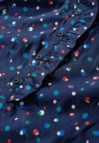 Navyblauwe shirt met multikleurige stippen. Heeft een rimpel-kraag en een knopenlijst. Gemaakt van lichtgewicht stof.