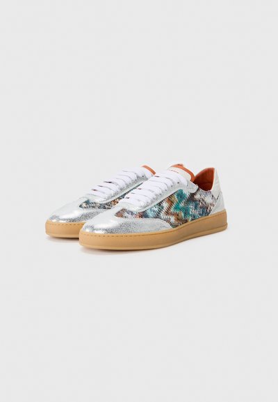 Lace-up sneakers with a silver metallic finish, multicolored textured detailing, and a tan rubber sole. Features white laces and an orange interior.