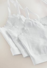 Tre canotte bianche in cotone con bordi in pizzo ondulato e spalline sottili, caratterizzate da una consistenza morbida e un design semplice e senza cuciture.