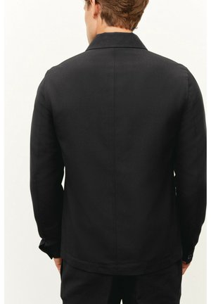 Černá bunda s rovný střihem, dlouhými rukávy a manžetami na knoflíky. Hladká textura a minimalistický design s klasickým límcem.