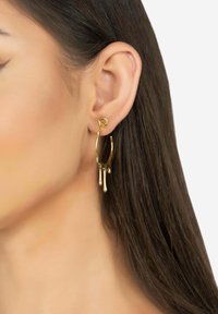 Goldene Creolen mit einem tropfenden Design und glänzender Oberfläche. Leichtgewichtig hängen sie unter dem Ohrläppchen und sorgen für einen markanten Look.