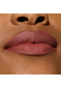 Labial mate sobre labios llenos, en un suave color malva. Los labios son lisos con una textura fina, sobre una tez clara de tono medio.