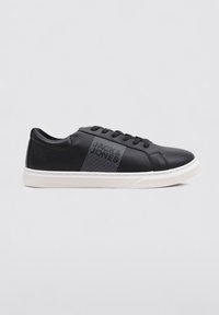 Zapatillas de cuero negro con suela de goma blanca en contraste, con un sutil diseño a rayas en el lateral, punta redonda y seis ojetes.