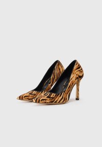 Chaussures à talons avec un bout pointu, arborant un motif rayé tigre brun et noir sur une texture semblable à du daim, et un intérieur noir brillant.