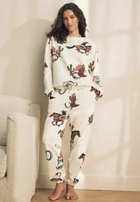 Set de trening alb, cu un design tipărit de cowboy, cai, cactuși și accesorii de rodeo; material moale cu bordură elastică la pantaloni.