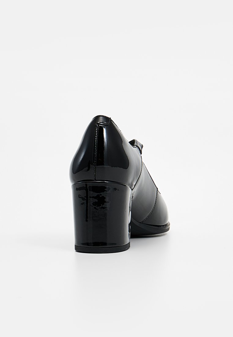 Schwarzer Lackleder-High-Heel-Schuh mit spitz zulaufender Zehenpartie und einem dicken Absatz. Verfügt über eine glatte Textur und ein minimalistisches Design.