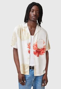 Camisa de manga corta floral en crema con estampados de flores rojas y rosas. Incluye un bolsillo en el pecho, tejido suave y un corte relajado.