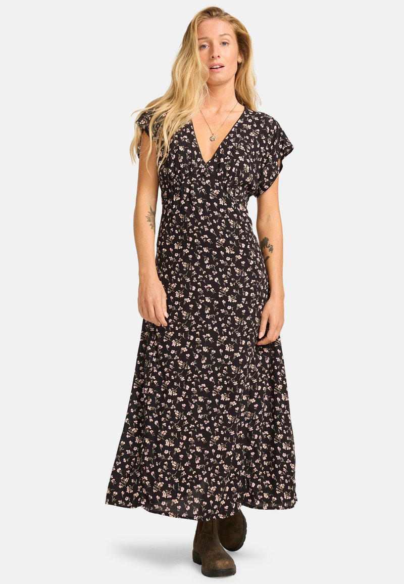 Vestido largo negro con flores, con un escote en V profundo, mangas cortas con vuelo y una silueta fluida, que presenta pequeños patrones de flores rosas y blancas.