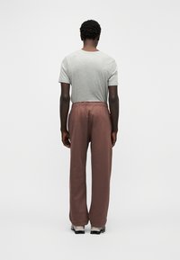 Pilkas trumpomis rankovėmis marškinėlis derinamas su laisvomis bordo spalvos sportinėmis kelnėmis su elastinga juosmens juosta. Paprastas, be puošmenų dizainas.