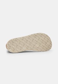 Semelle d'une chaussure avec une surface texturée, présentant un motif circulaire en caoutchouc beige clair ; orteil légèrement arrondi avec un bord lisse.
