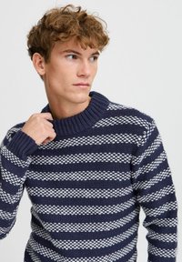 Maglione a righe blu navy e bianche in maglia con colletto a coste e tessuto testurizzato. Presenta righe sovrapposte in un design accogliente.