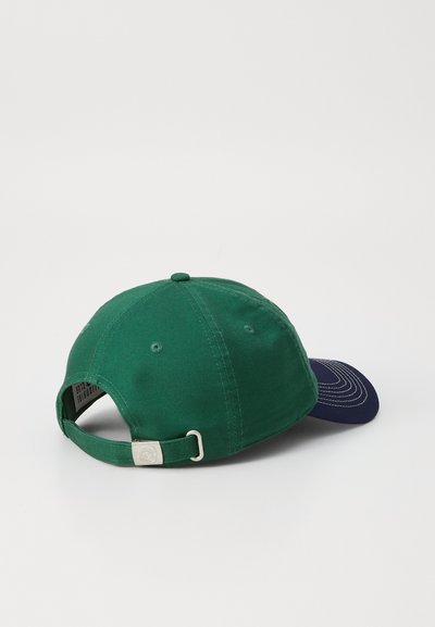 Casquette en coton verte avec un pic marine, bandeau ajustable, matériel en métal argenté et trous de ventilation. Texture lisse avec des coutures contrastantes.