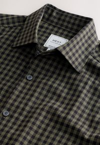 Camicia a quadri verde scuro e nera, in cotone, colletto con bottoni, chiusura con bottoni e etichetta. Taglio regular fit.