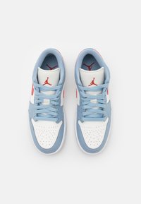 Une paire de baskets blanches et bleu clair avec des logos Jumpman rouges, des lacets bleu clair et une zone perforée au niveau des orteils, vue de dessus sur un fond blanc.