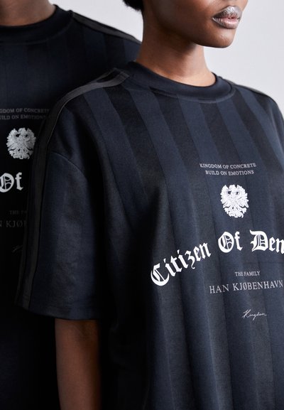 Sort grafisk t-shirt med vertikale striber, tekstdesign i hvid på forsiden og skulderdetaljer. Fremstillet af blødt stof.